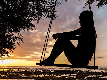 woman sitting on swing watching sunset