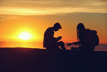 people playing music at beach sunset